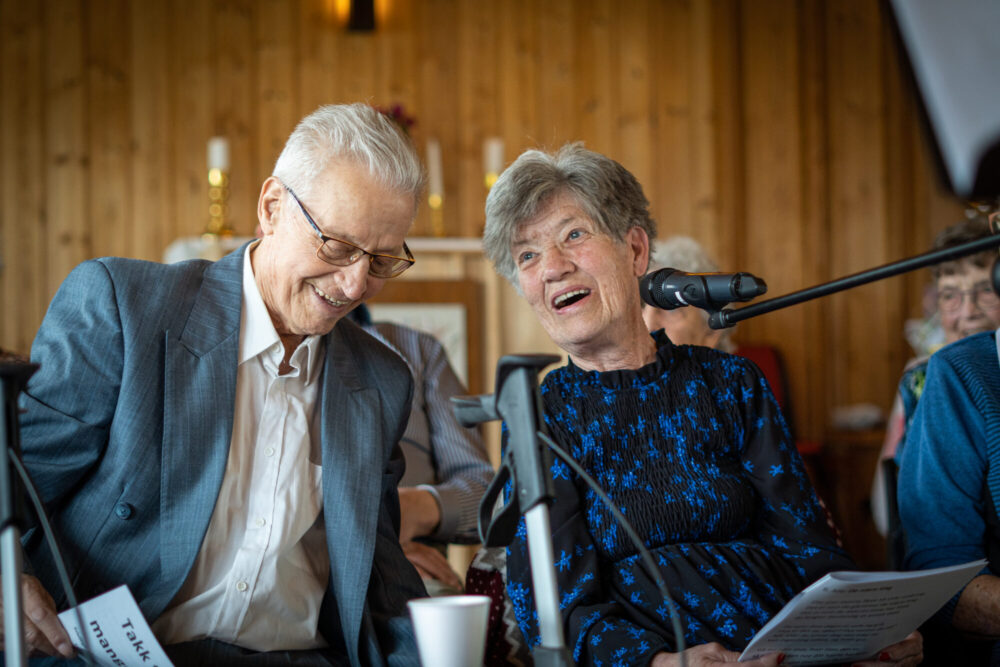 En eldre mann og en eldre kvinne lener seg mot hverandre. De ler.